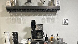 Una estación de café con una cafetera Keurig, tazas de café, azúcar y un molinillo.