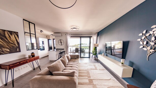 A modern living room with a sofa, a TV, and a dining area.