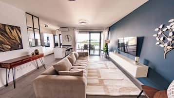 A modern living room with a sofa, a TV, and a dining area.