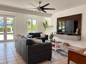 Una sala moderna con un sofá modular, una mesa de centro y un televisor de pantalla plana montado en la pared.