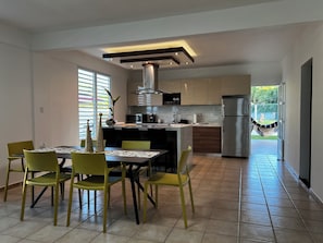 Een moderne keuken met een centraal eiland, gele stoelen en een eettafel.