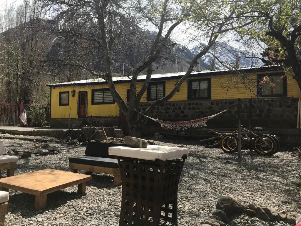 A yellow building with a stone wall, a hammock, and a bicycle.