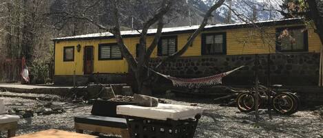 A yellow building with a stone wall, a hammock, and a bicycle.