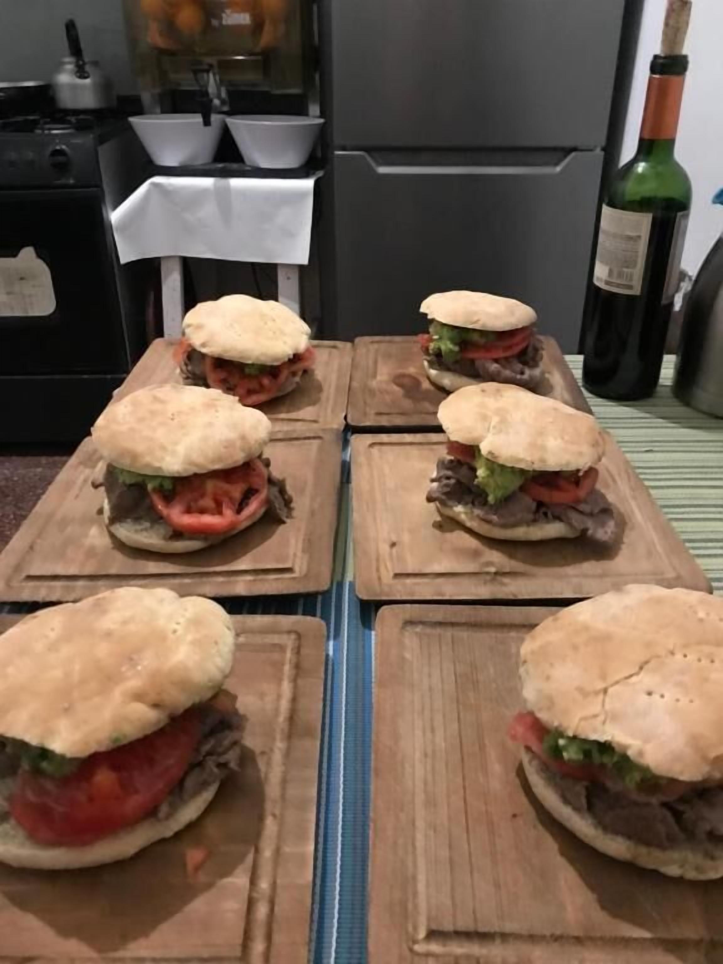 Quatre sandwichs présentés sur des planches en bois, dans une cuisine.