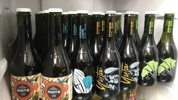 Een koelkast gevuld met verschillende flessen bier, waaronder merken zoals 'MATE' en 'Raubier'.