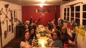 Un groupe de personnes s’est rassemblé autour d’une table dans une pièce dont un mur était rouge, qui comportait une fenêtre et dont les murs étaient ornés de divers objets.