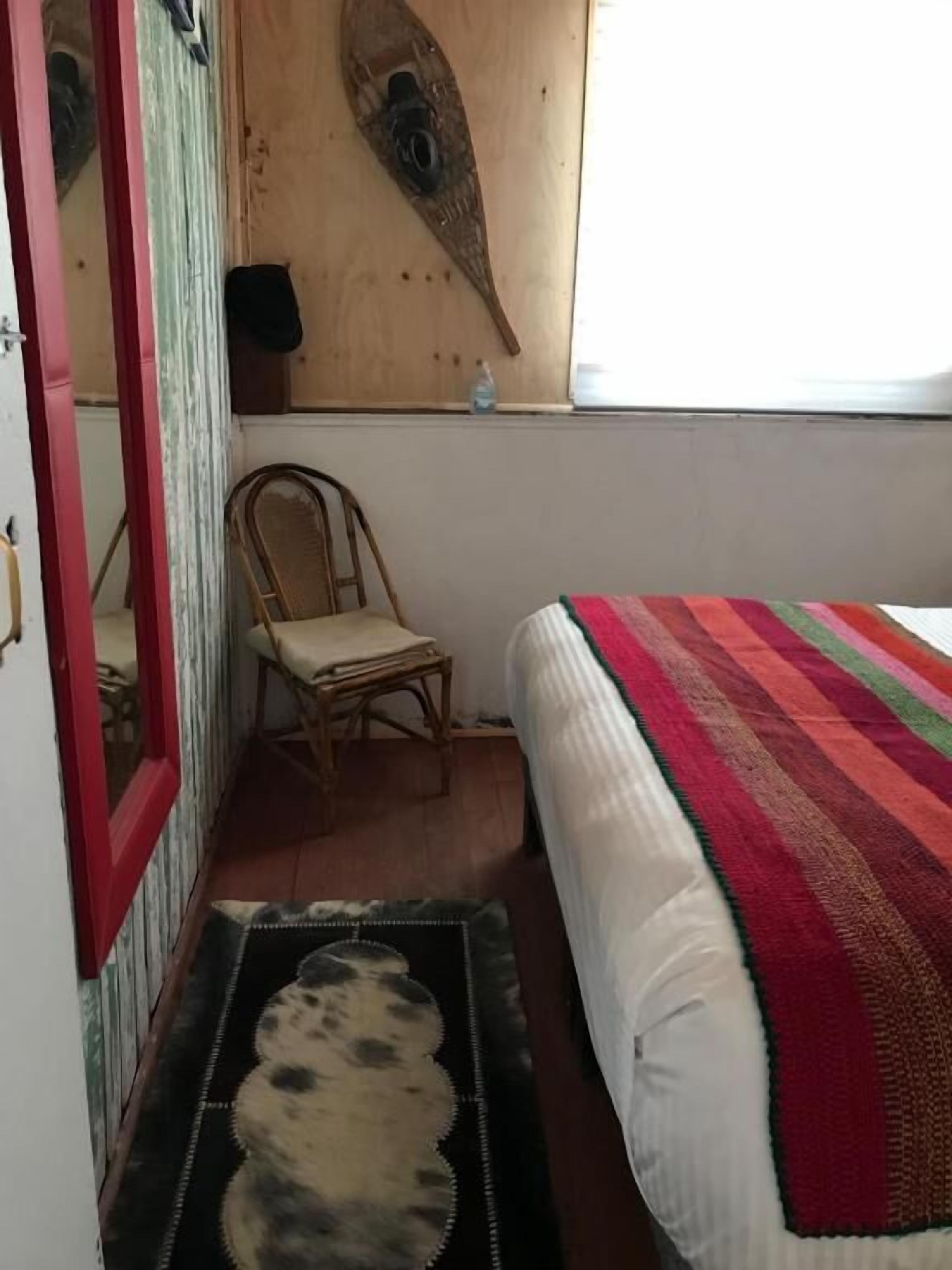 A bedroom with a bed, a chair, a rug, and a wall-mounted decoration.