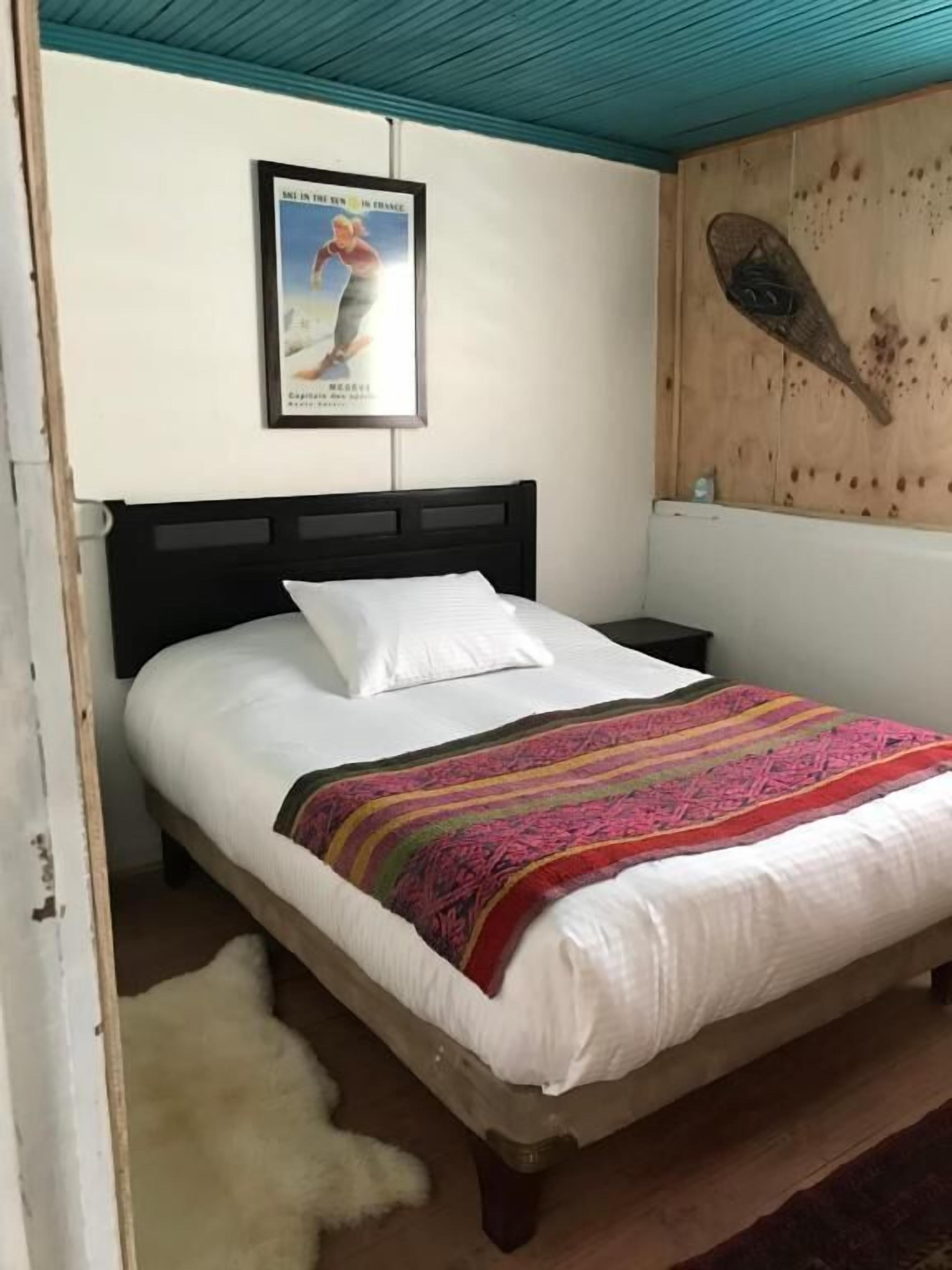 A bedroom with a bed, a wooden headboard, a poster on the wall, and a wooden wall panel.