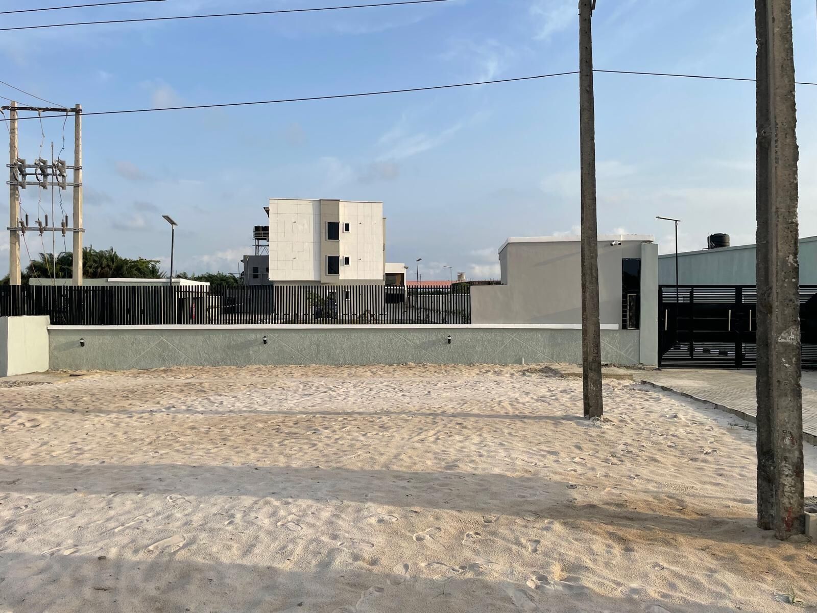 Un edificio de techo plano y base de concreto, rodeado por una valla metálica.