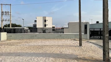 Un edificio de techo plano y base de concreto, rodeado por una valla metálica.