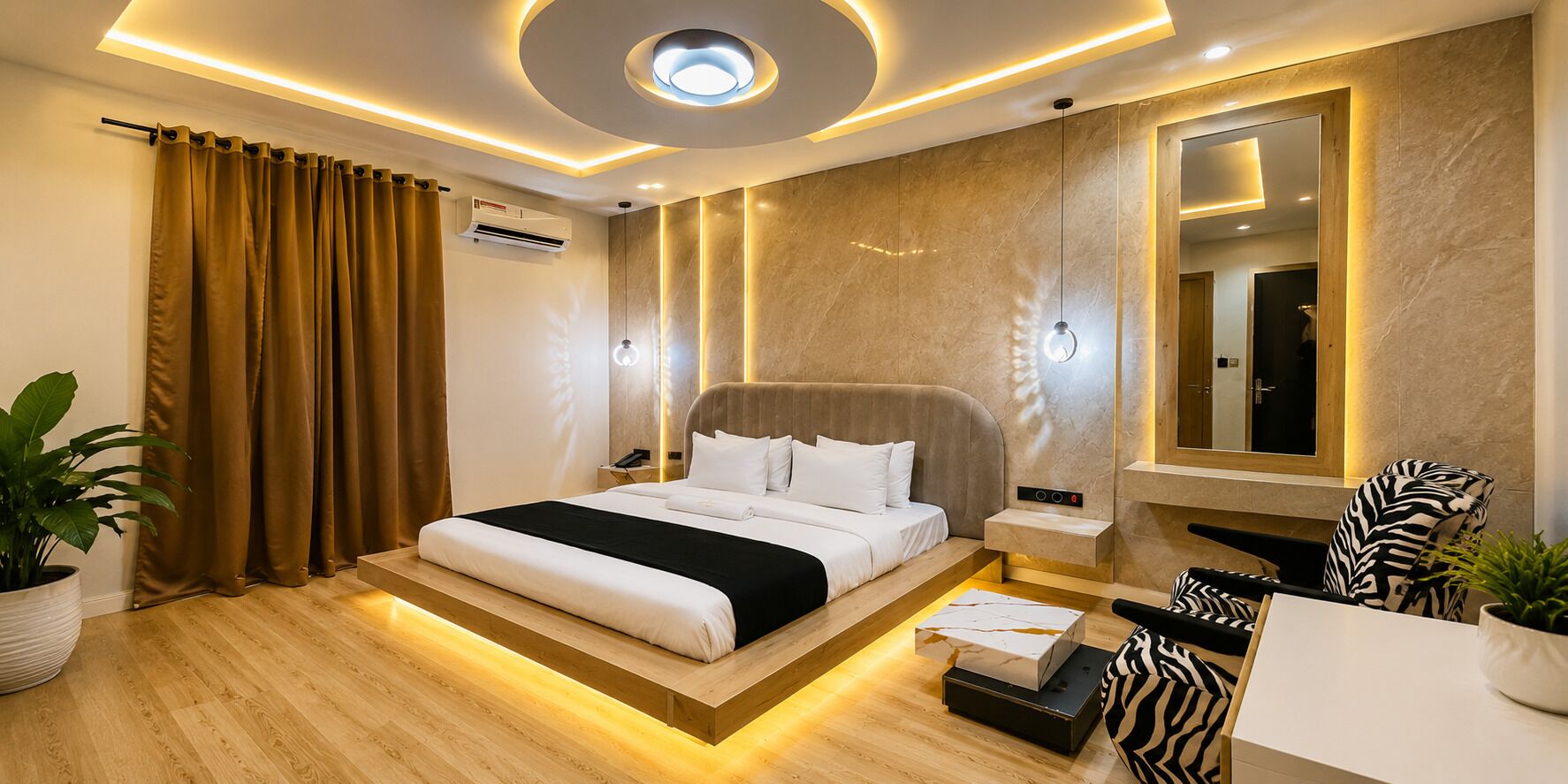 A modern hotel room with a bed, bedside table, mirror, and a seating area with a zebra-patterned chair.