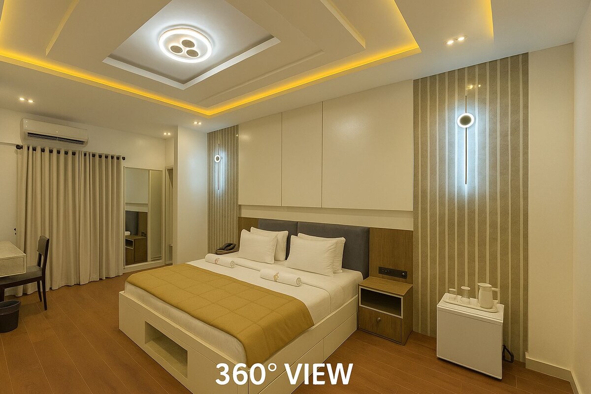 A modern hotel room with a large bed, bedside tables, a desk, and a wardrobe.