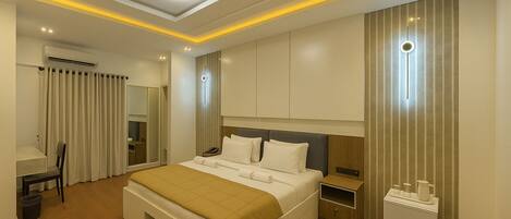A modern hotel room with a large bed, bedside tables, a desk, and a wardrobe.