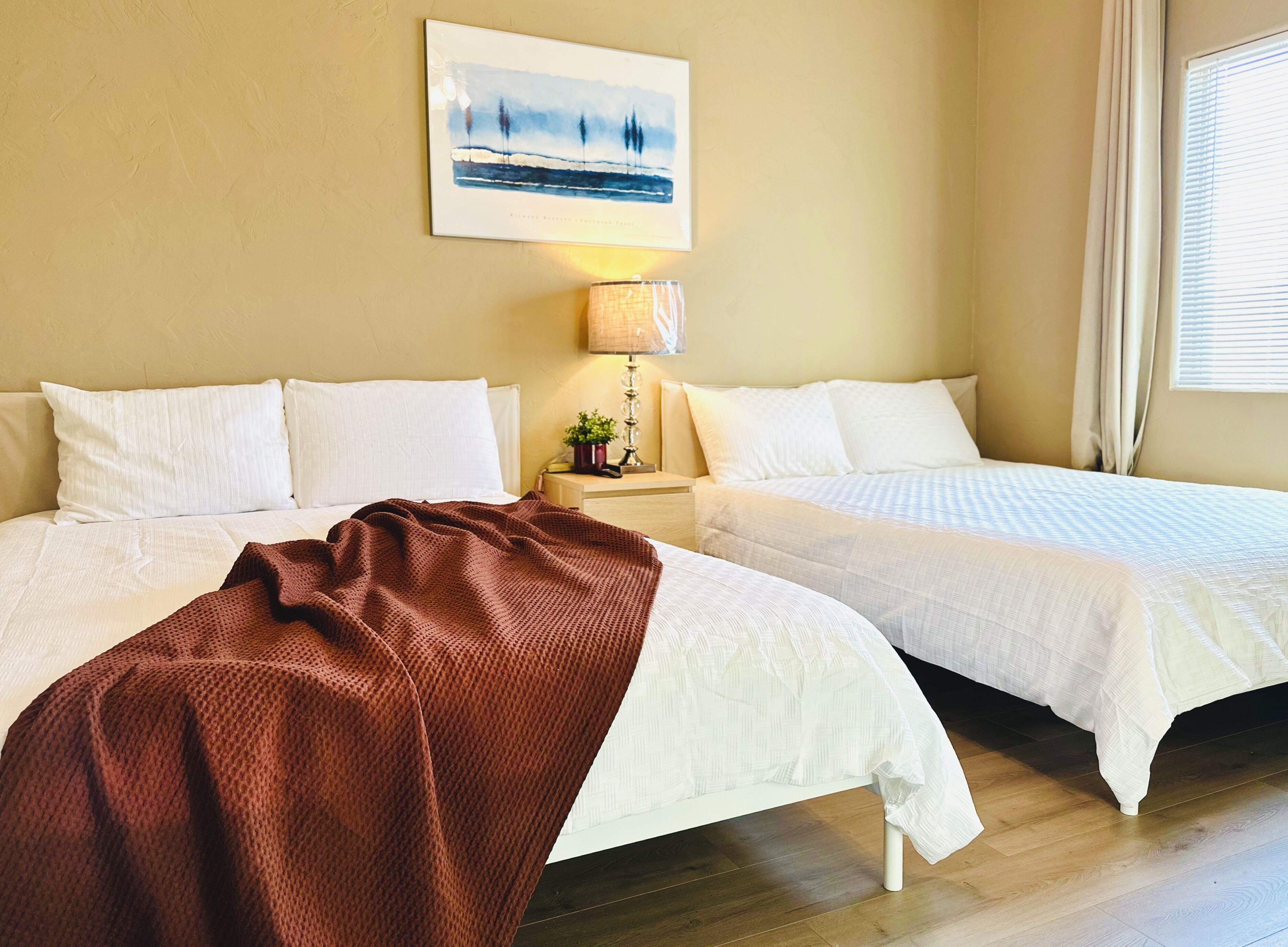 Une chambre d’hôtel avec deux lits, une table de chevet avec une lampe et un tableau au mur.
