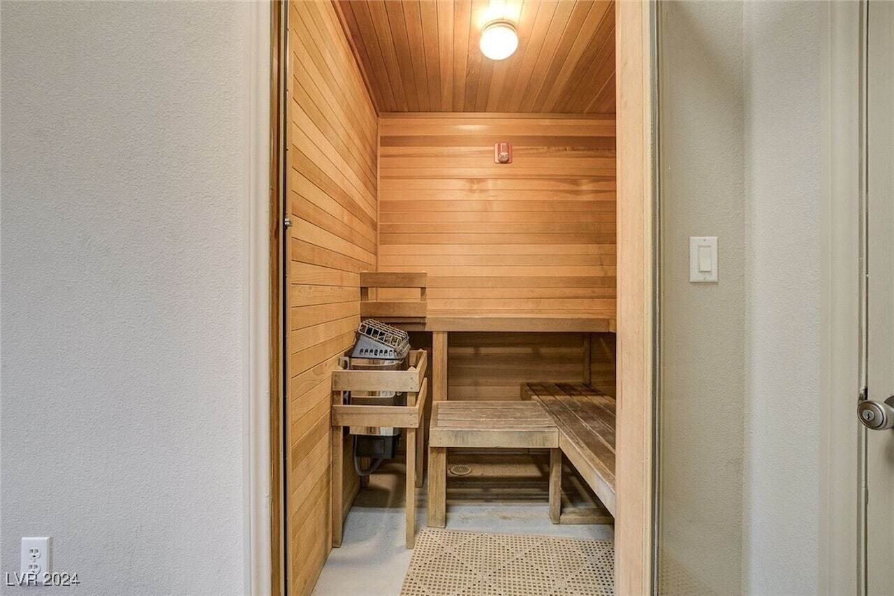 Una sauna con paredes y bancos de madera, una pequeña mesa y una cesta.
