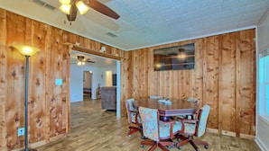 A room with wooden walls, a ceiling fan, a dining table with chairs, and a TV mounted on the wall. - Lakefront Home -Private Dock, Fishing and Stunning Views (Milam)