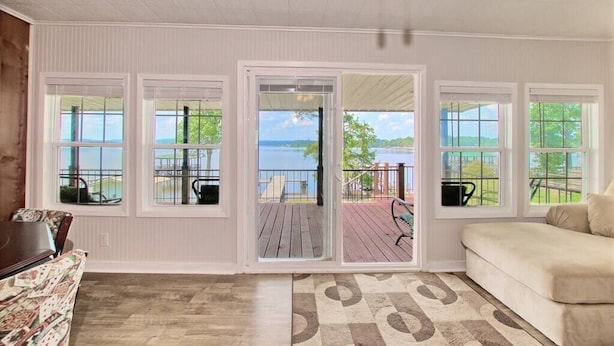 A room with large windows offering a view of a deck and a lake. - Lakefront Home -Private Dock, Fishing and Stunning Views (Milam)