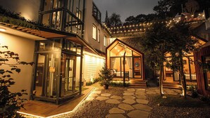 Una casa moderna con entrada de vidrio, un camino de piedra y un pequeño árbol en primer plano.