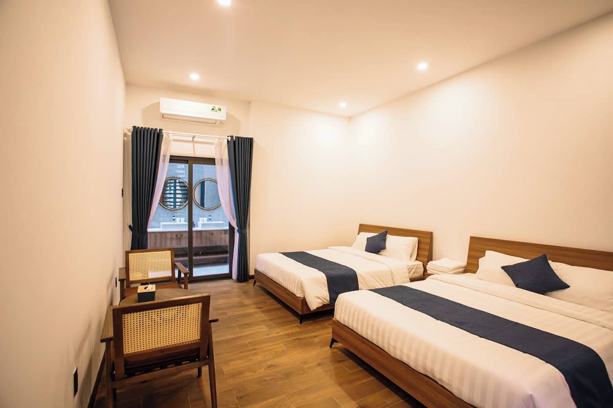 Habitación de hotel con dos camas, un escritorio y una silla.