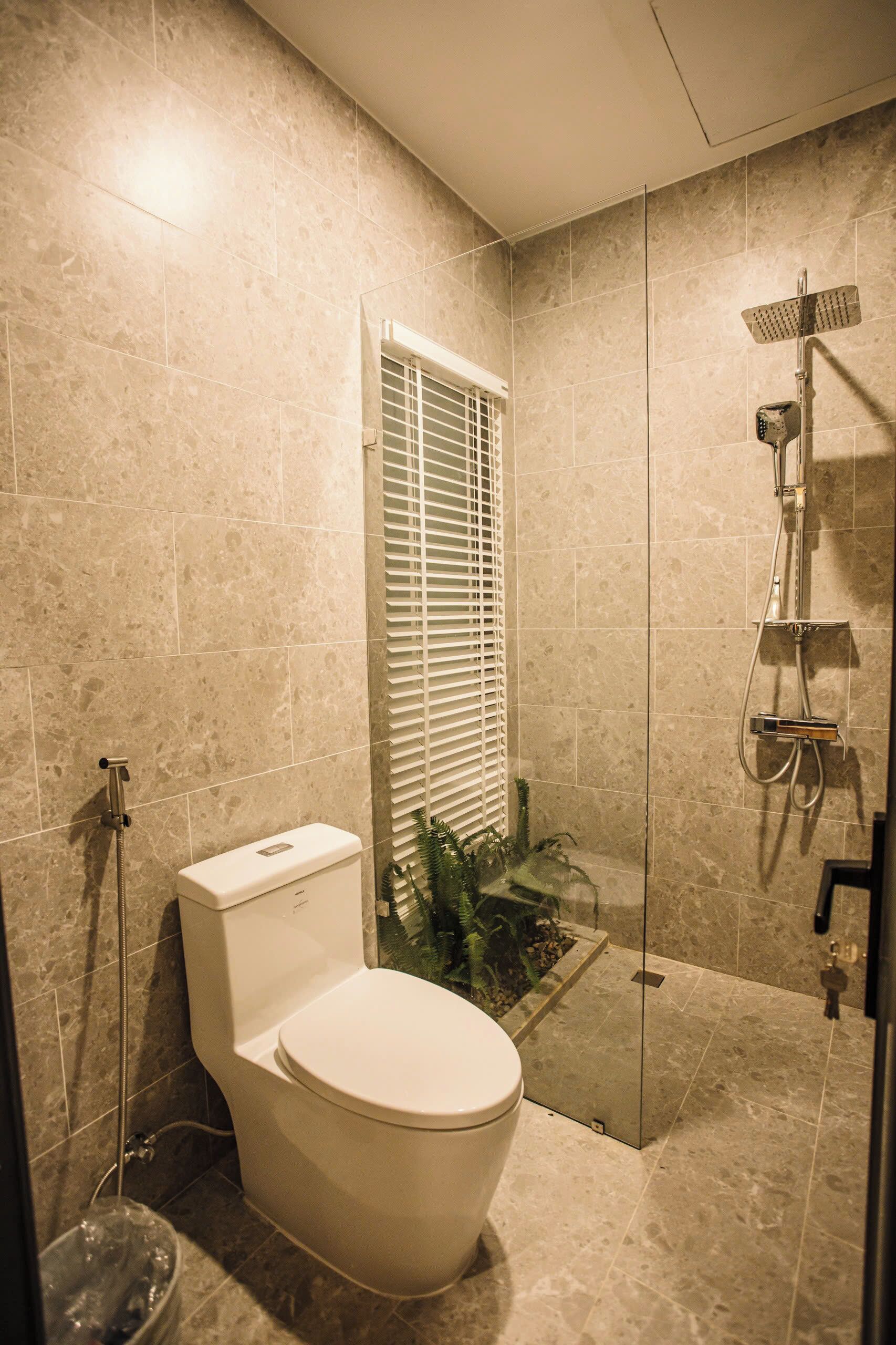 A modern bathroom with a toilet, shower, and glass-enclosed shower area.