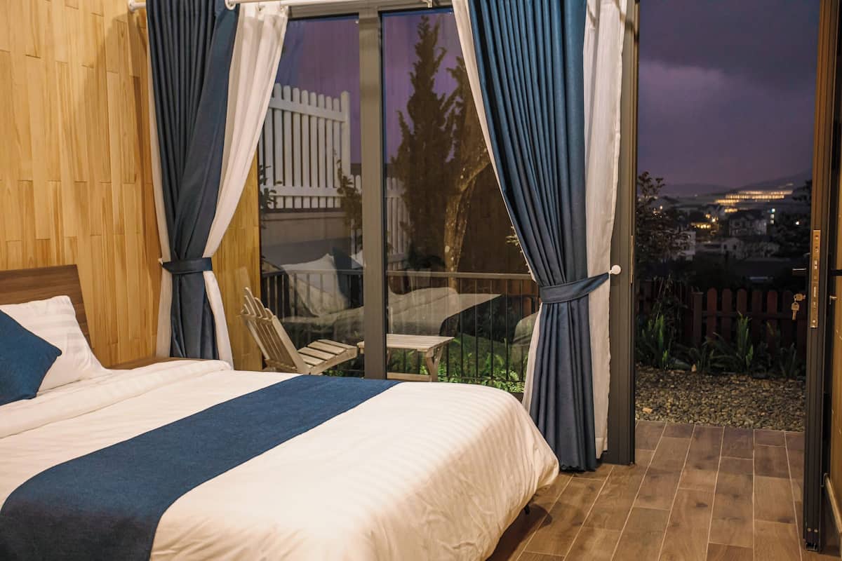 Un dormitorio con cama, cortinas y vistas a un balcón con mesa y sillas.