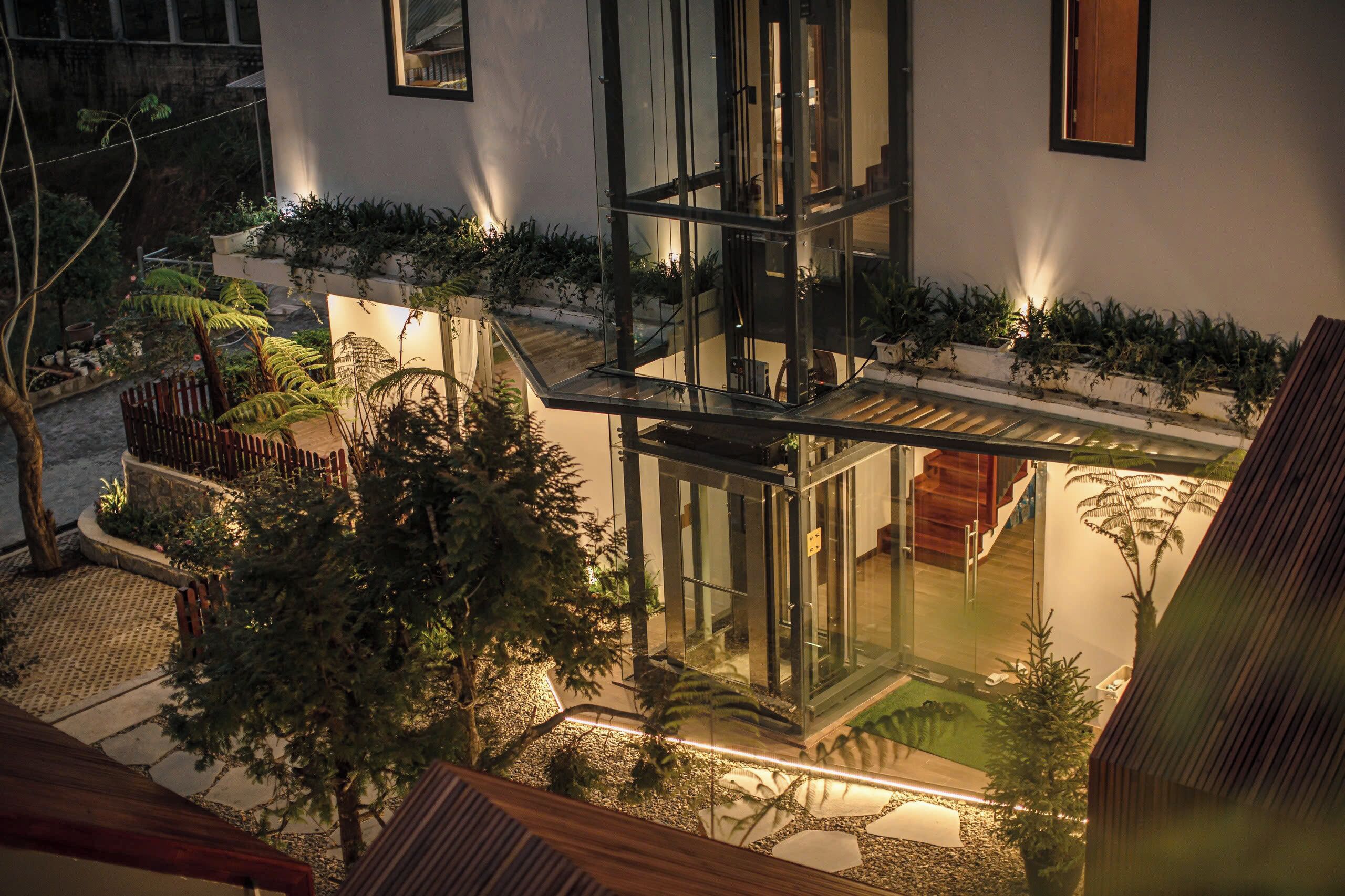 A modern building with a glass facade, outdoor seating area, and a well-maintained garden.