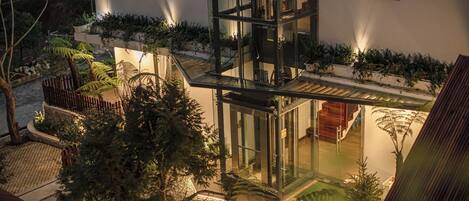 A modern building with a glass facade, outdoor seating area, and a well-maintained garden.