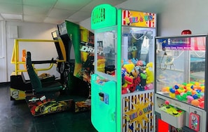A gaming area with arcade machines, including a racing game and claw machines.