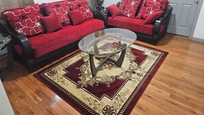 Una sala de estar con dos sofás rojos, una mesa de centro de vidrio y un tapete estampado.