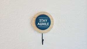 A circular wooden sign with the text "STAY AWAY" mounted on a white wall.