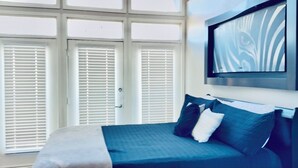 A bedroom with a bed, pillows, and a TV mounted on the wall.