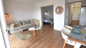 Una sala de estar moderna con un sofá, dos sillones, una mesita redonda y una mesa de comedor con sillas.
