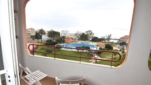 Un balcón con vistas a una piscina, un área verde y edificios circundantes.