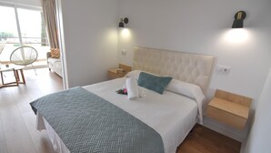 Una habitación de hotel moderna con una cama grande, una mesita de noche, una silla y vistas al exterior.