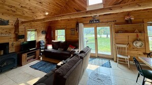 Interior de una cabaña con chimenea, sofá, televisión y comedor.