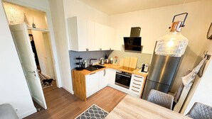 A compact kitchen with white cabinets, a wooden countertop, a built-in oven, and a stainless steel refrigerator. - Vacation apartment Meehr Glowe - Villa Rosa - Holiday apartment Mee(h)r (Glowe)