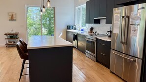 Una cocina moderna con una isla central, electrodomésticos de acero inoxidable y vistas al exterior.