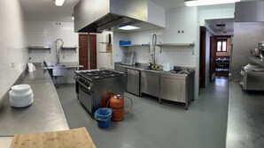 Een professionele keuken met roestvrijstalen apparatuur, een gasfornuis, een vaatwasser en een spoelbak.