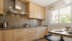 A modern kitchen with granite countertops, wooden cabinets, and a stainless steel Bosch range hood. - Sunny Terrace Apt in Golf Valley with Pool (Estepona)