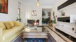 A modern living room with a sofa, coffee table, and a TV mounted on the wall. - Sunny Terrace Apt in Golf Valley with Pool (Estepona)