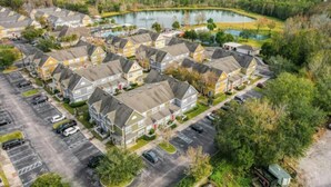 Een woonwijk met meerdere twee-onder-een-kapwoningen, een parkeerplaats en een meer.