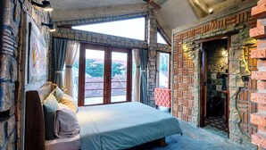 Un dormitorio con una cama grande, un ventilador de techo y vistas al exterior a través de un amplio ventanal.