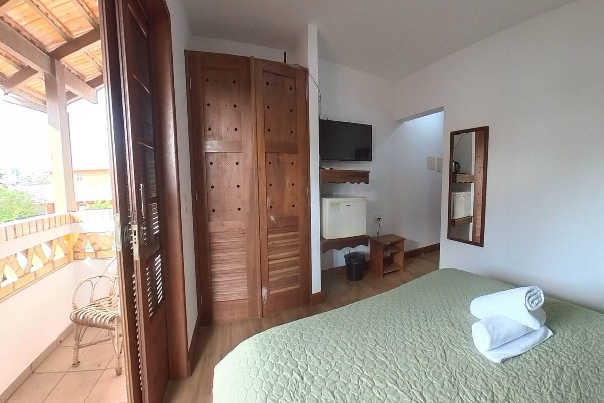 Ein Zimmer mit Bett, Fernseher, Kleiderschrank und Balkon.