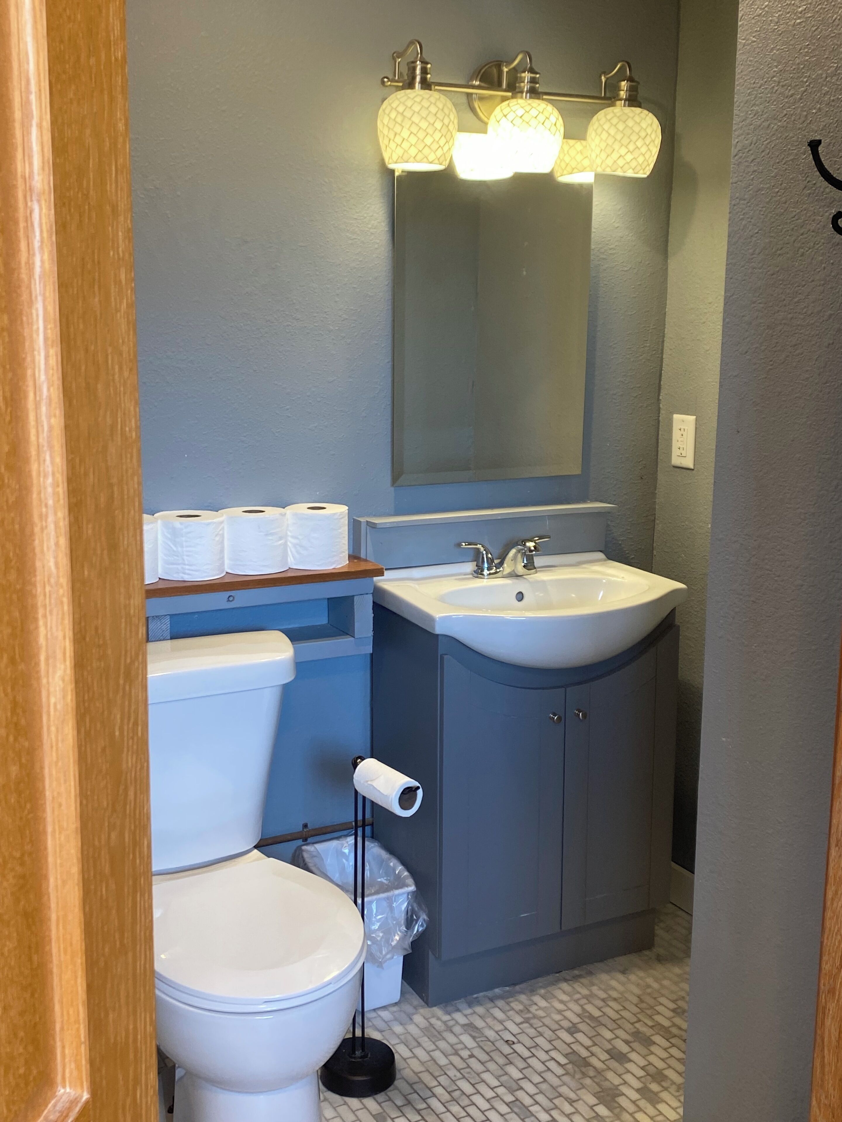 A bathroom with a toilet, sink, and mirror.