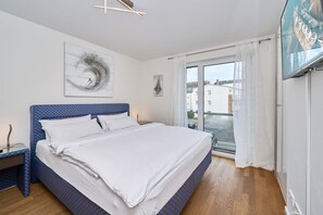 A bedroom with a bed, a nightstand, a painting, and a view through a window. - Moin by the sea! Hansastr. 5 a - Moin am Meer! Hansastr. 5 a 100 meters to the (Scharbeutz)