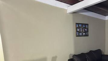 A dining area with a black table and grey chairs, a black sofa, and a framed photo collage on the wall.
