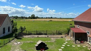 A rural landscape with a fenced field, a small wooden structure, and a red-roofed building. - Apartment 'Kuhstall' with Shared Terrace, Shared Garden and Wi-Fi (Werdum)