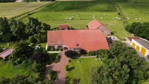 A large building with a red roof, surrounded by green fields and trees. - Apartment 'Kuhstall' with Shared Terrace, Shared Garden and Wi-Fi (Werdum)