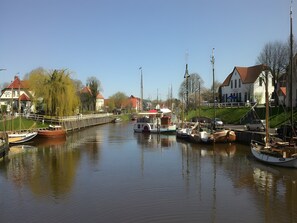 Un canal bordé de bateaux amarrés, un pont et des bâtiments le long de la rive.