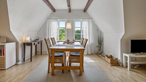Un comedor con una mesa de madera, sillas y una araña.